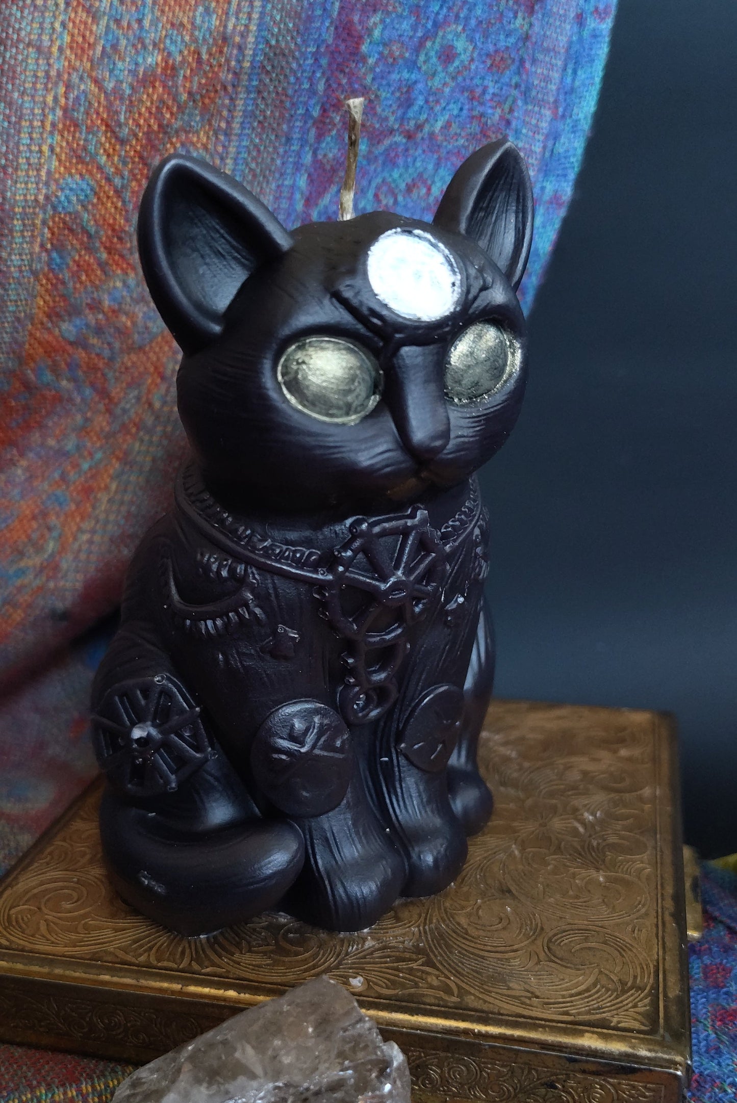 Decorative black cat figurine on a textured surface with a blue and orange pattern