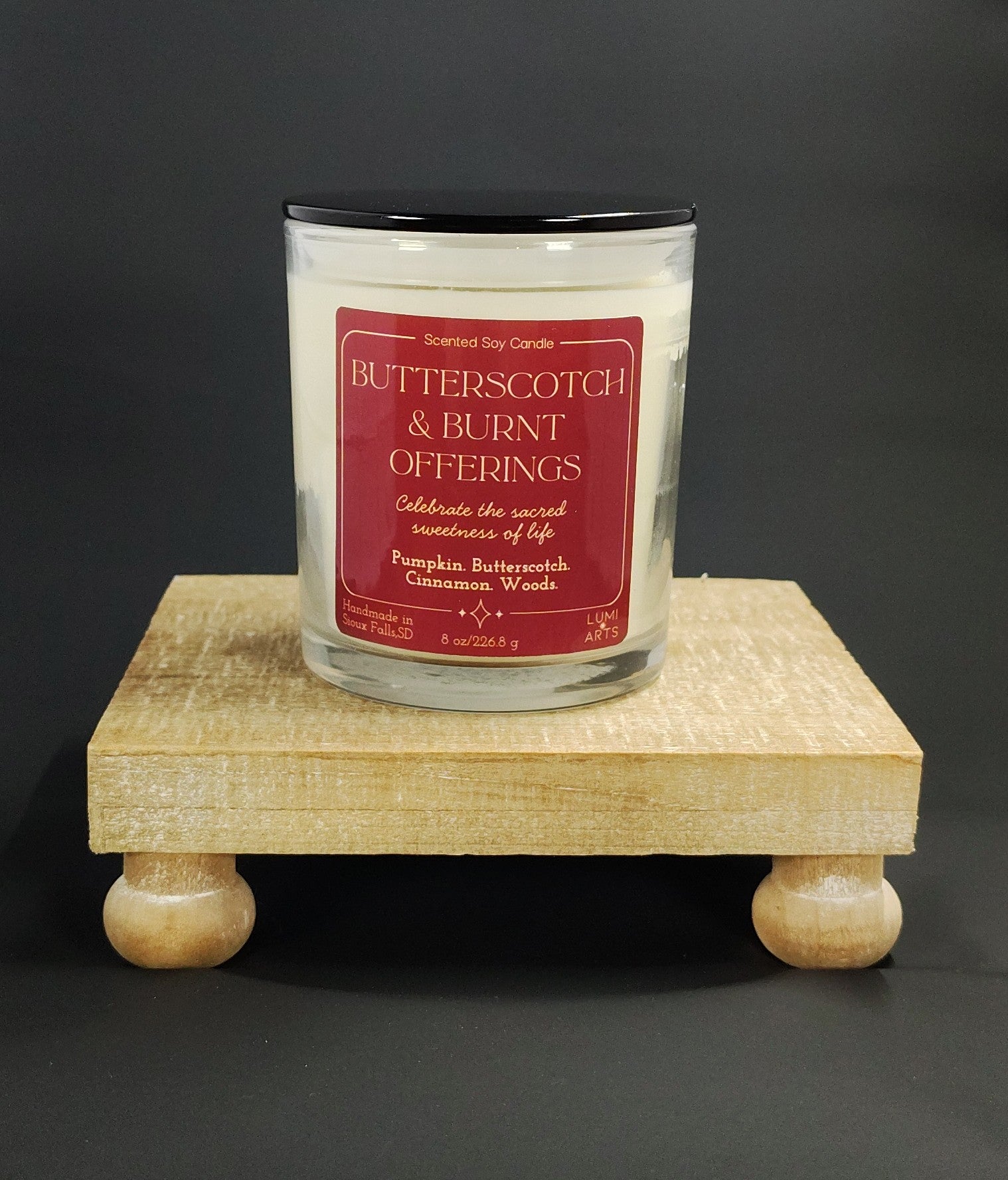 Candle with a red label on a wooden stand against a dark background