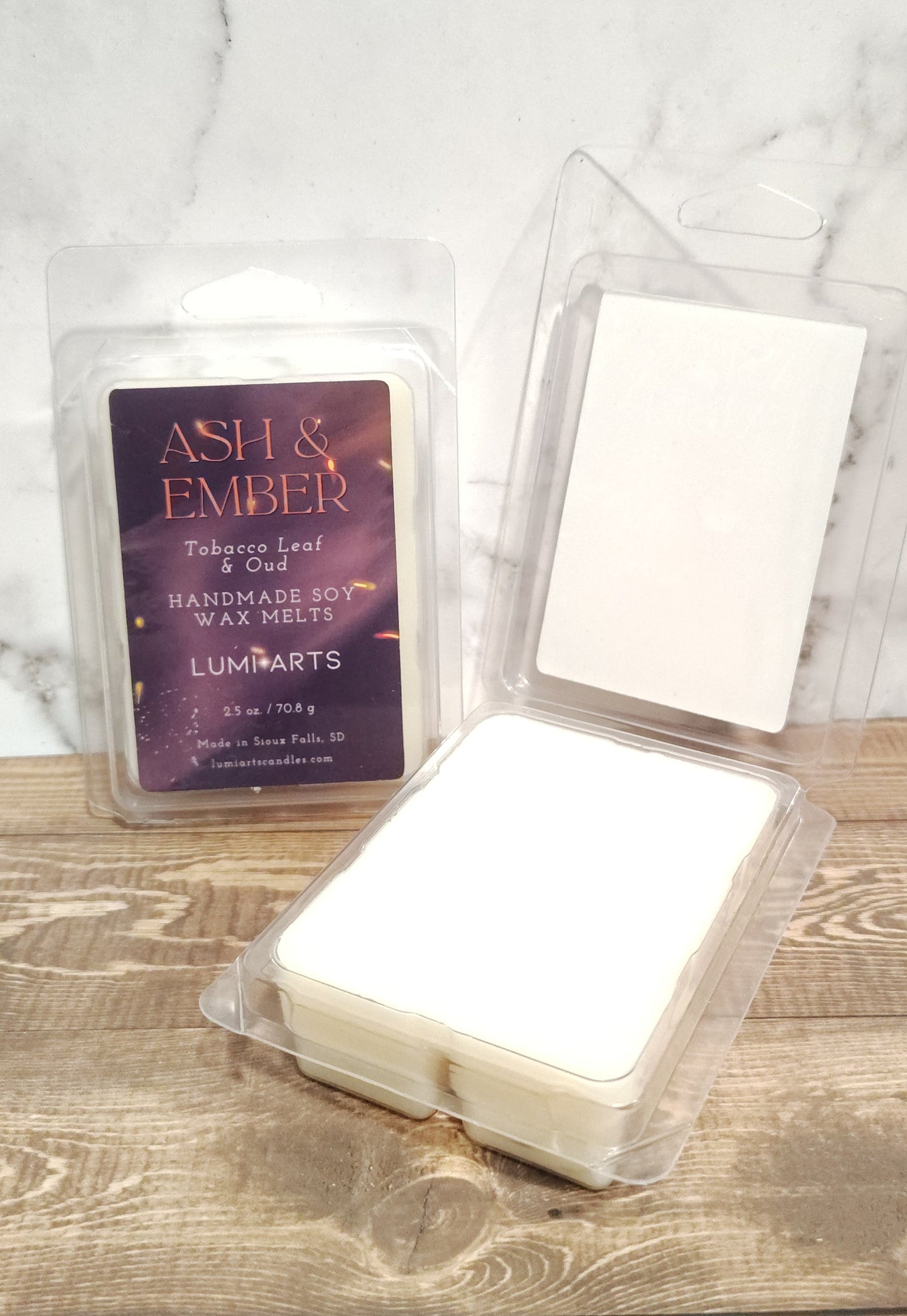 Three wax melts in clear containers on a marble and wooden surface