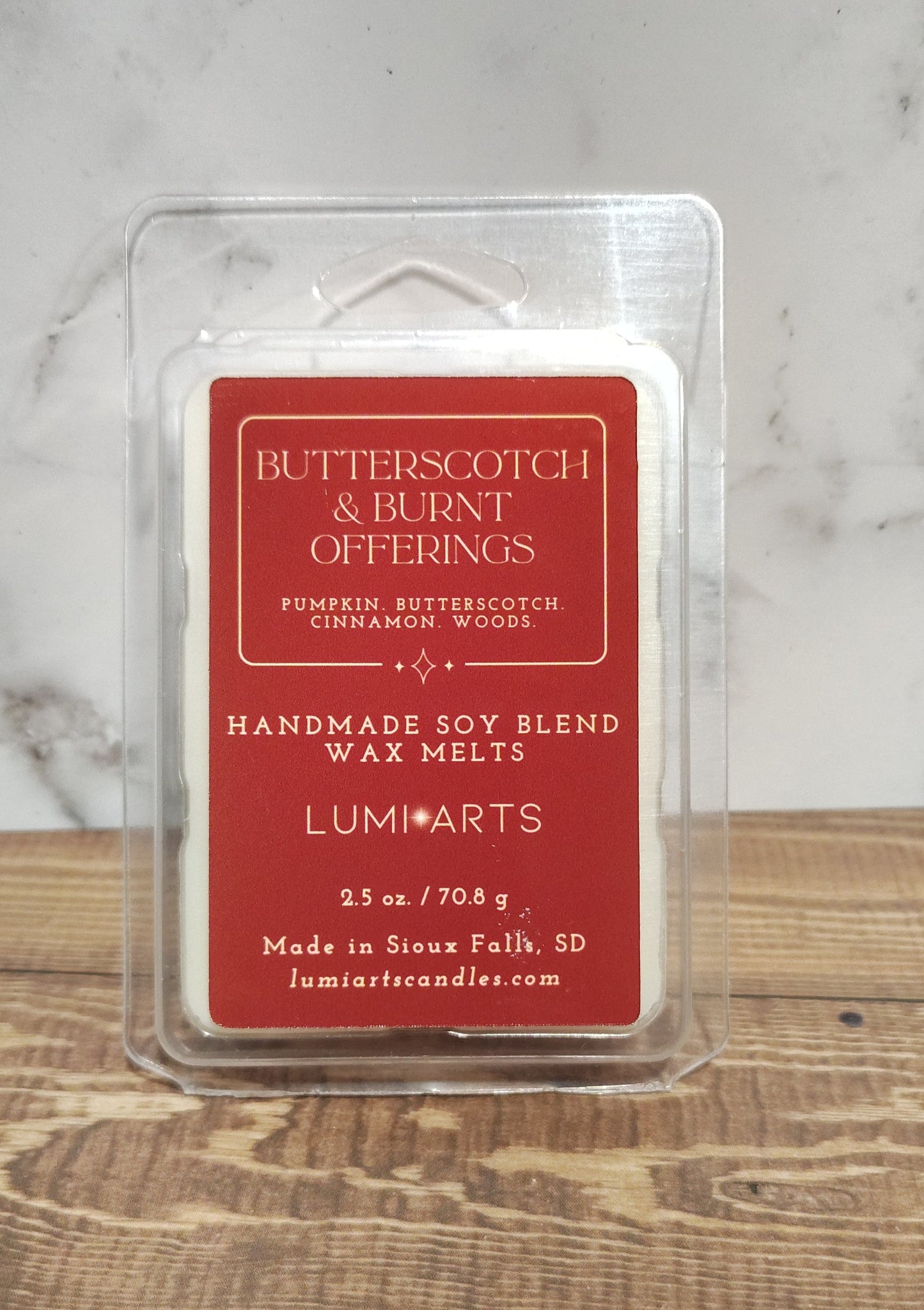 Butterfly Offings wax melt in a clear container on a marble and wooden surface