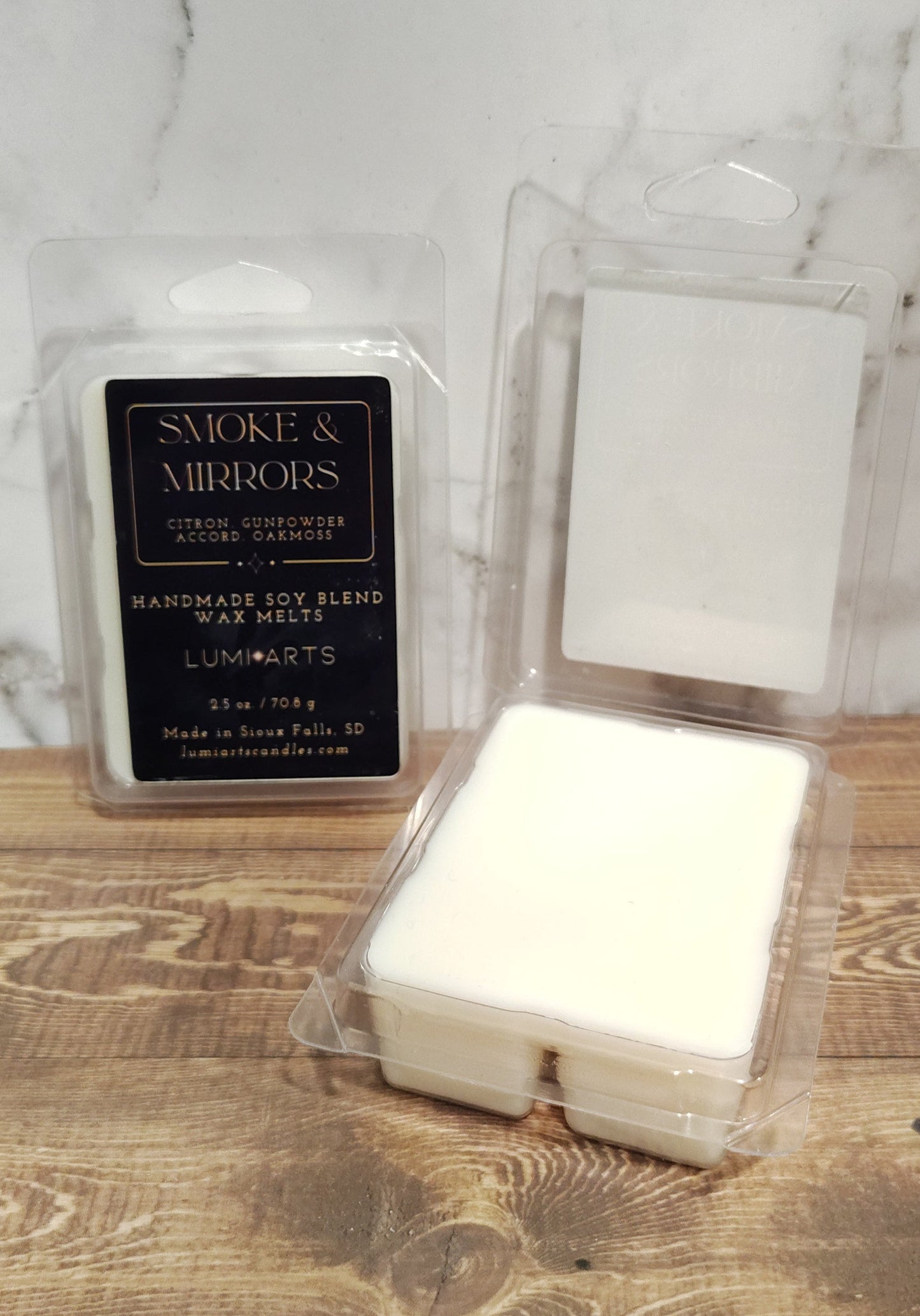 Two white candles in glass containers on a wooden surface with a marble background