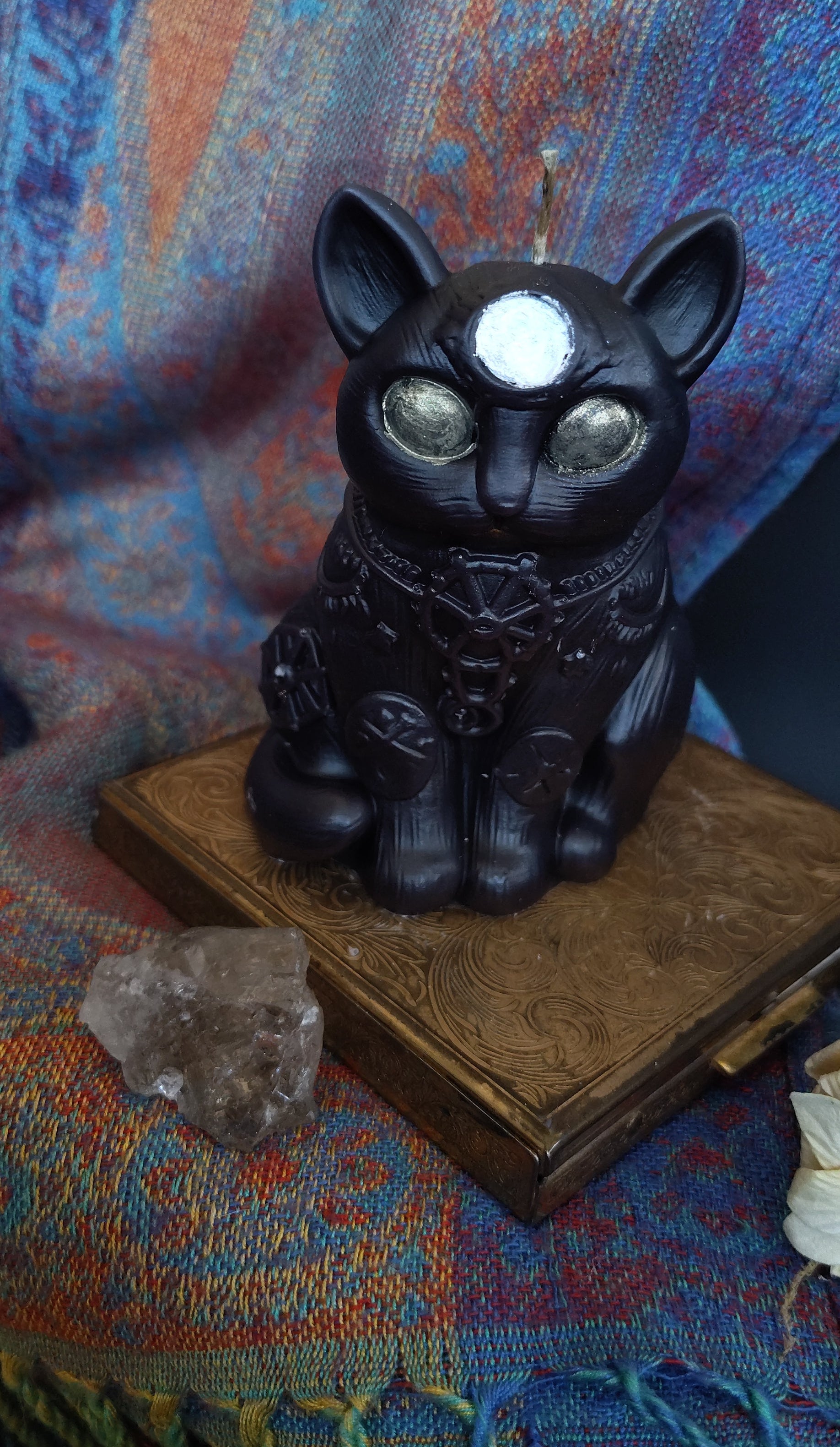 Black cat-shaped object on a textured fabric surface