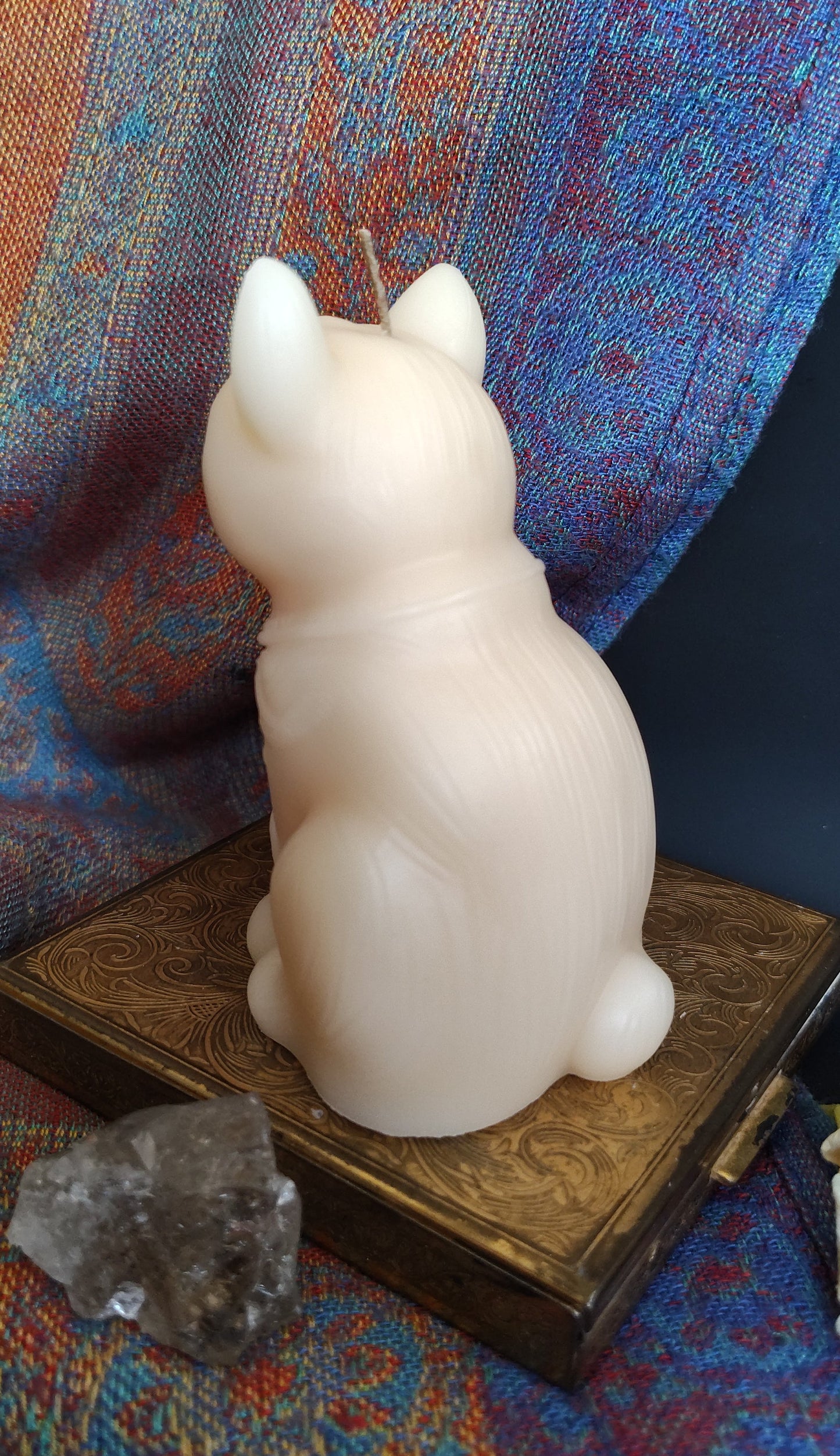 Small white cat figurine on a patterned fabric surface