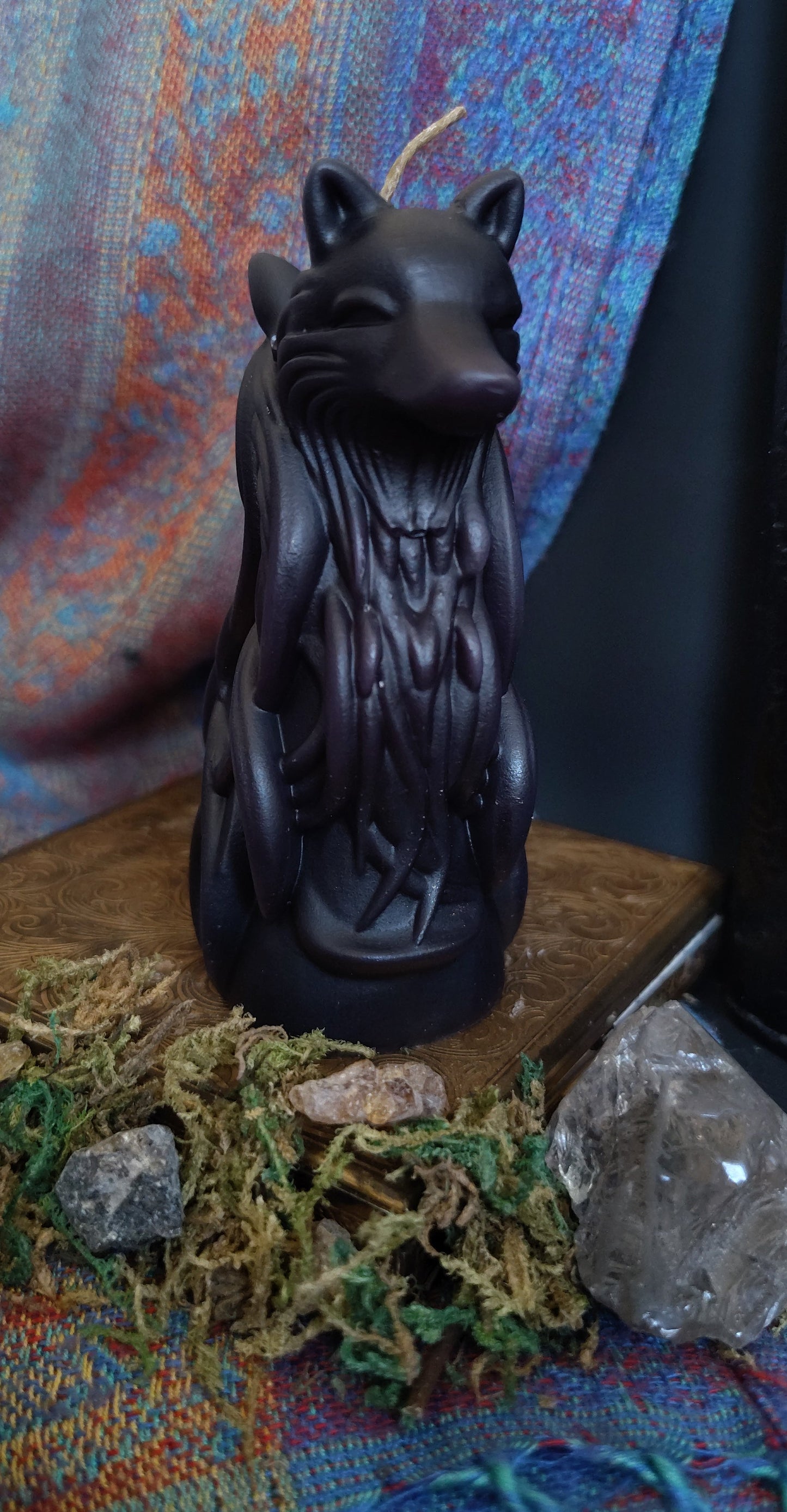Black two headed wolf figurine on a textured surface with crystals and stones