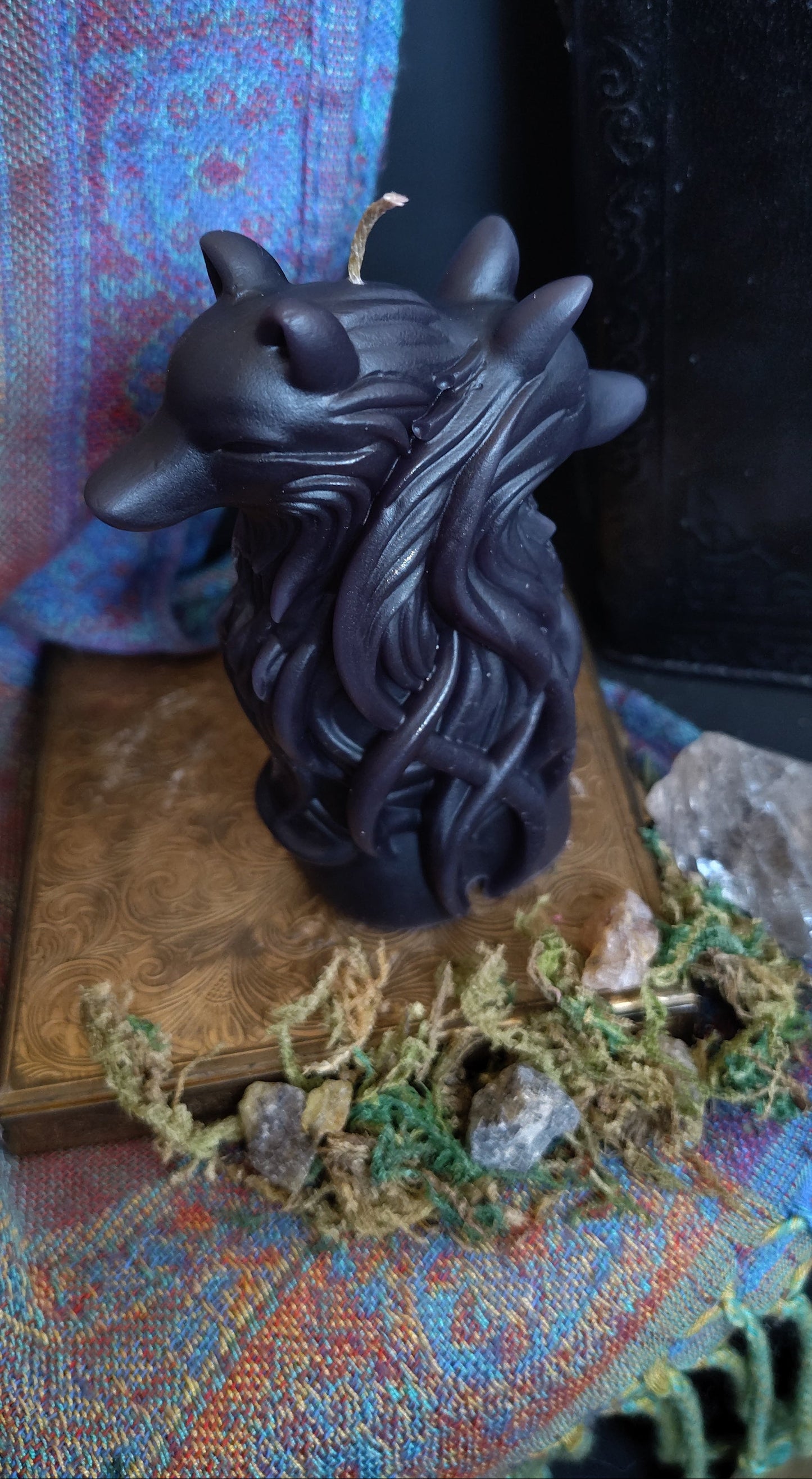 Black dual wolf head figurine on a textured surface with a book and decorative elements.