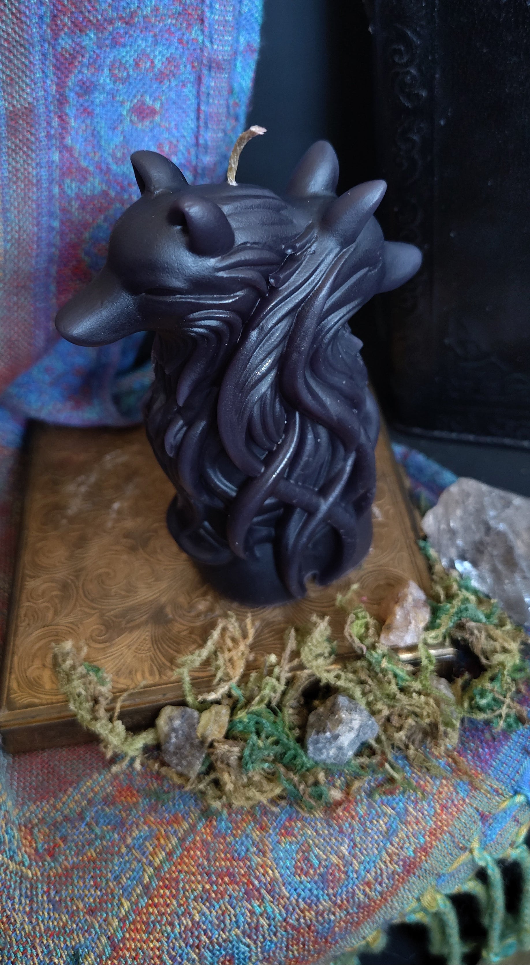 Black dual wolf head figurine on a textured surface with a book and decorative elements.