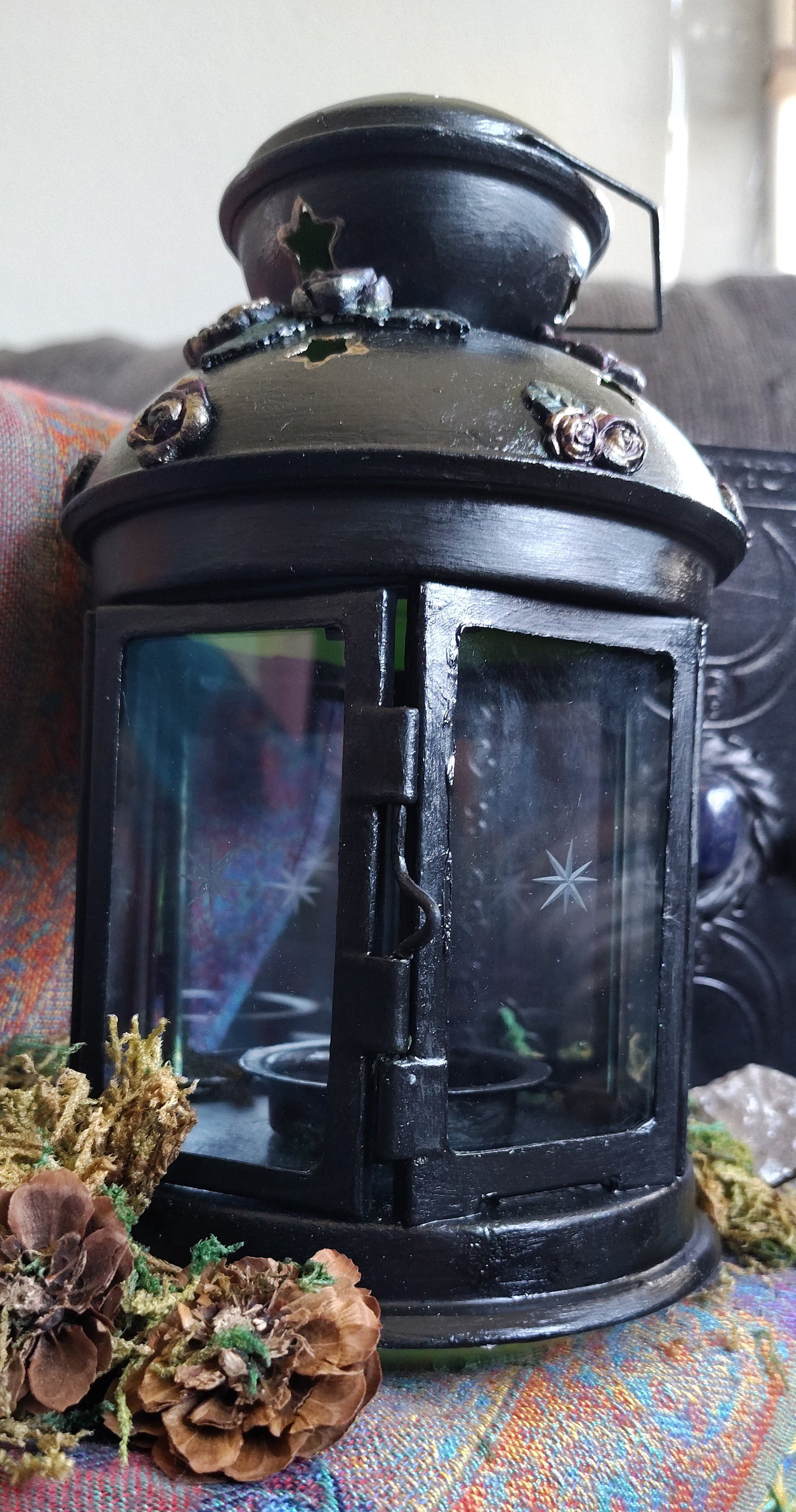 Lantern, surrounded by dried plants on a textured surface.