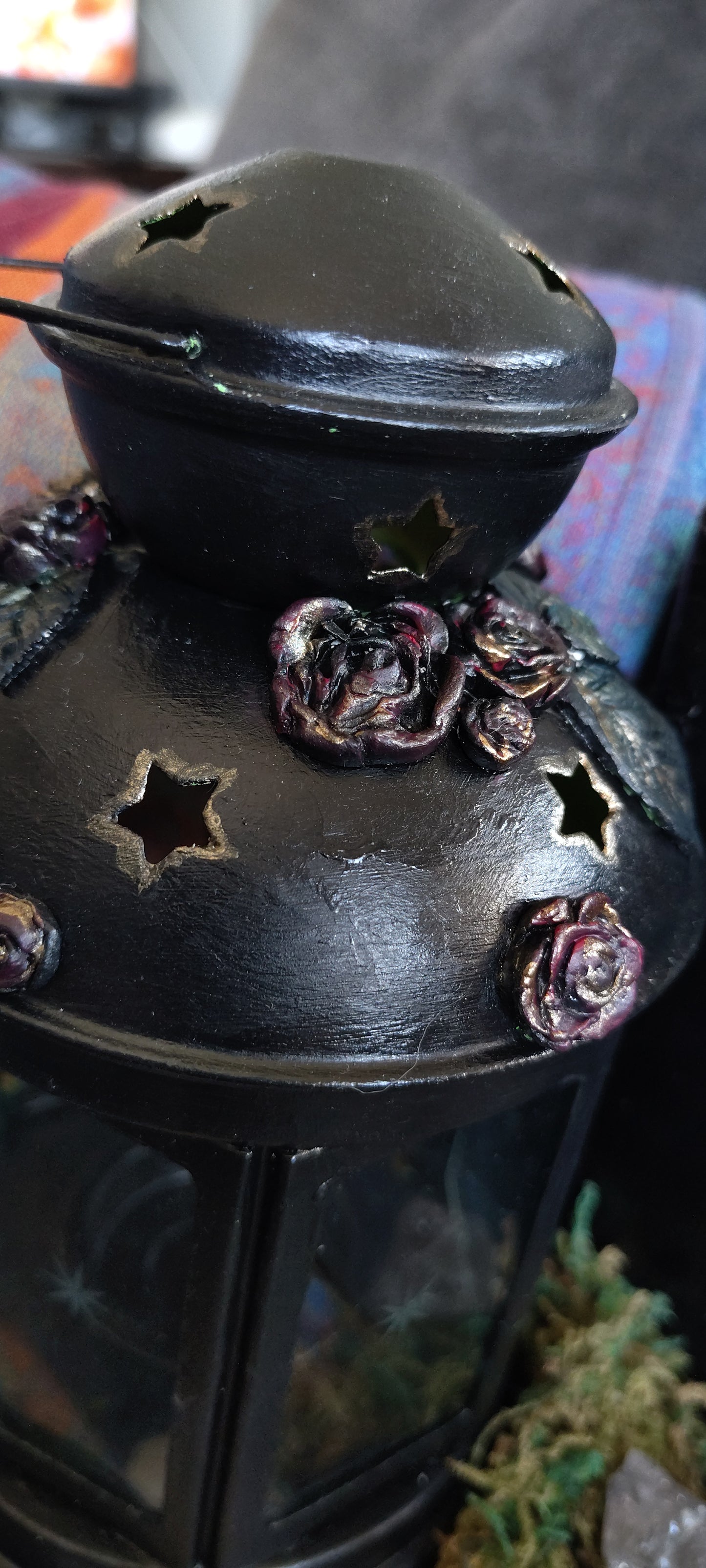 Decorative metal object with floral designs and star patterns on a blurred background