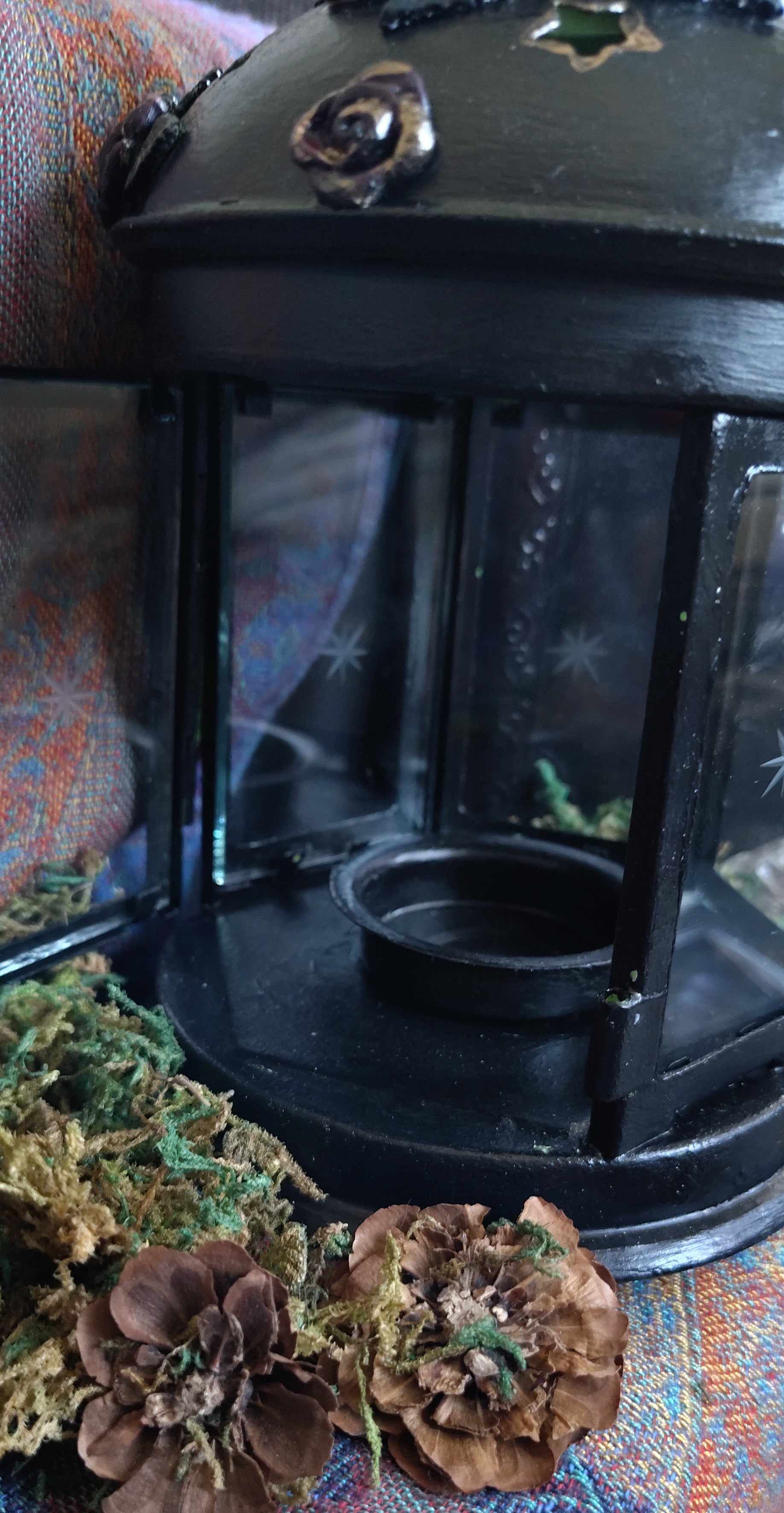 Lantern with pine cones on a textured fabric background