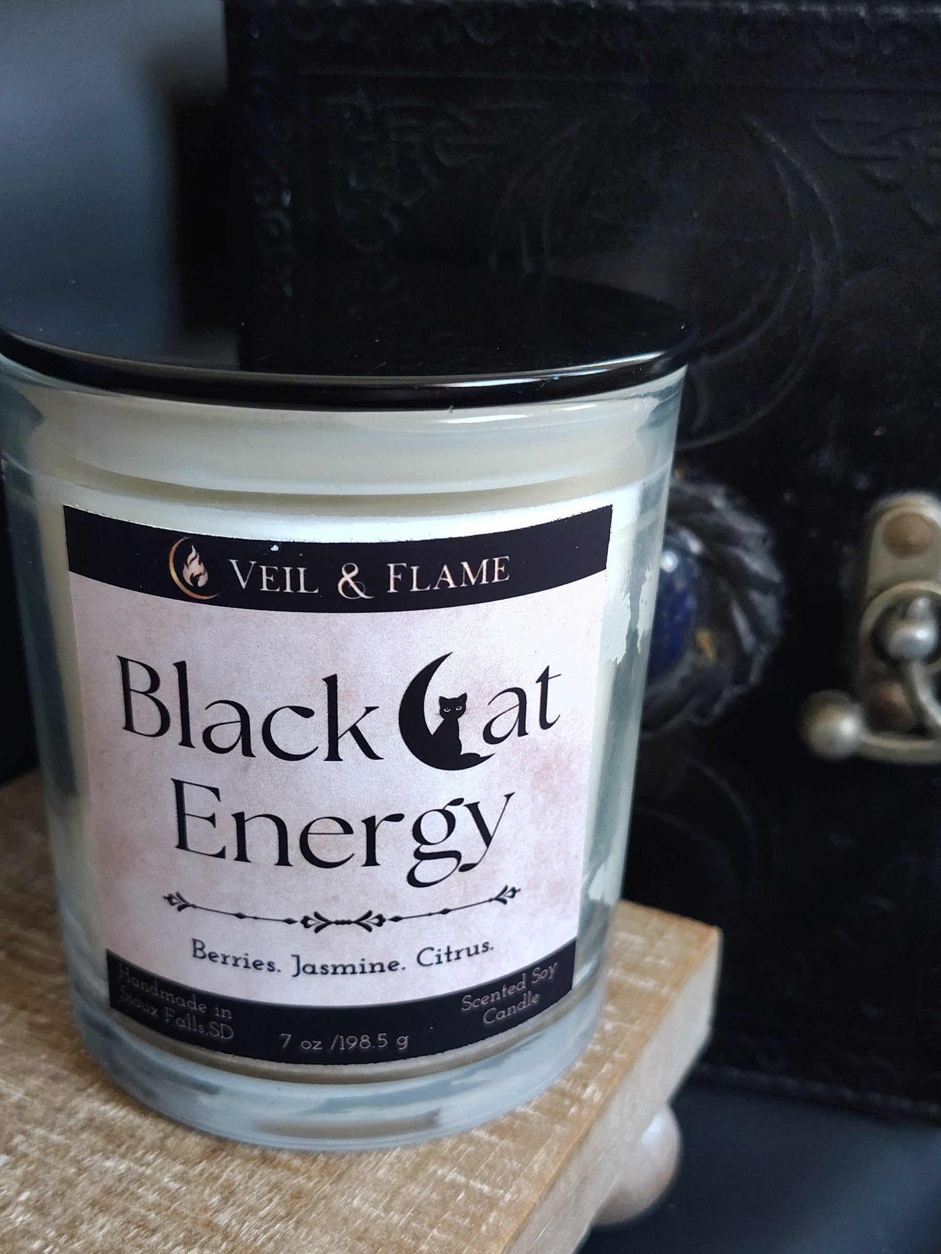 Candle labeled 'Black Cat Energy' by Veil & Flame on a textured surface.