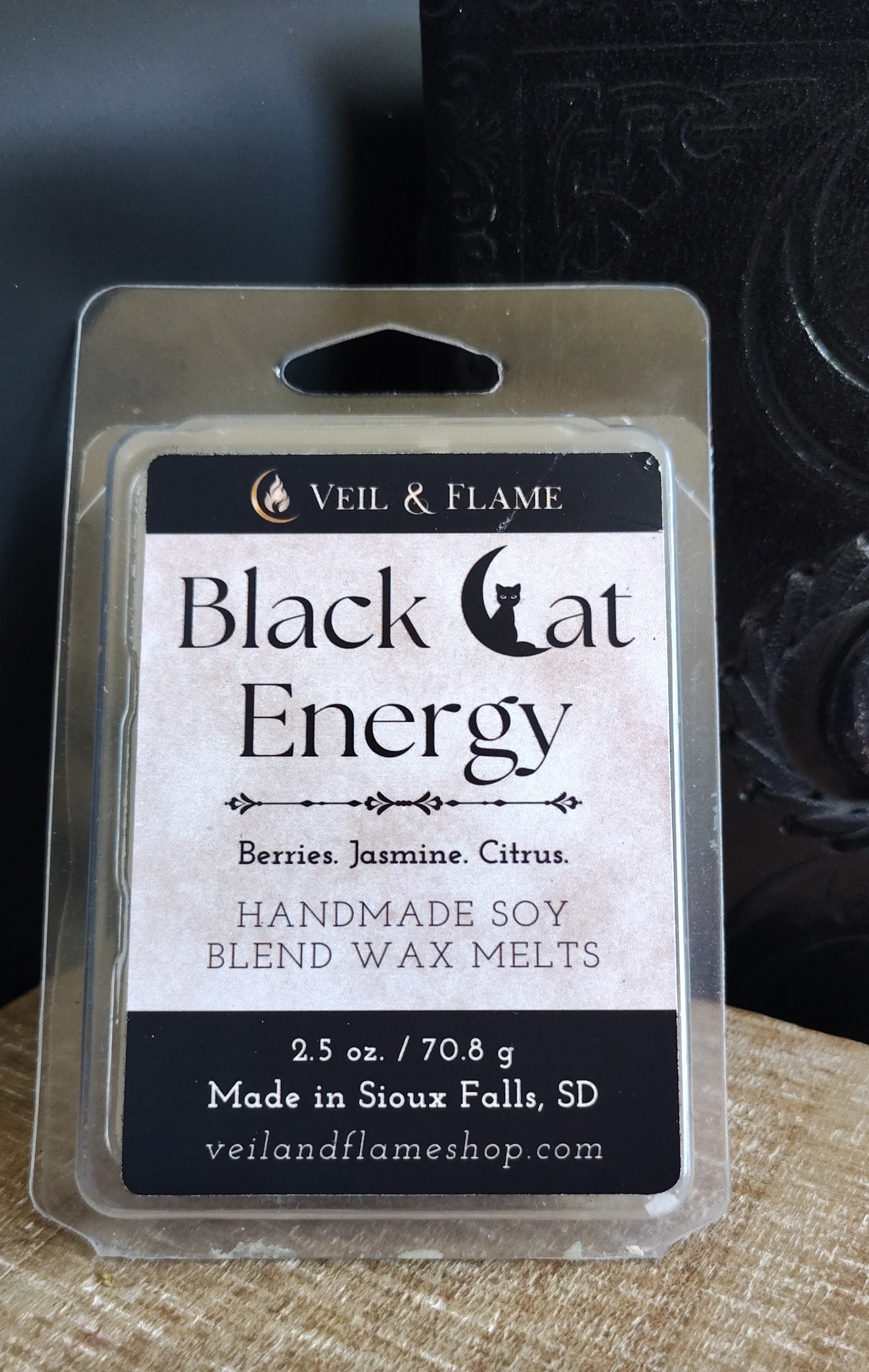 Veil & Flame Black Cat Energy wax melts packaging on a wooden surface