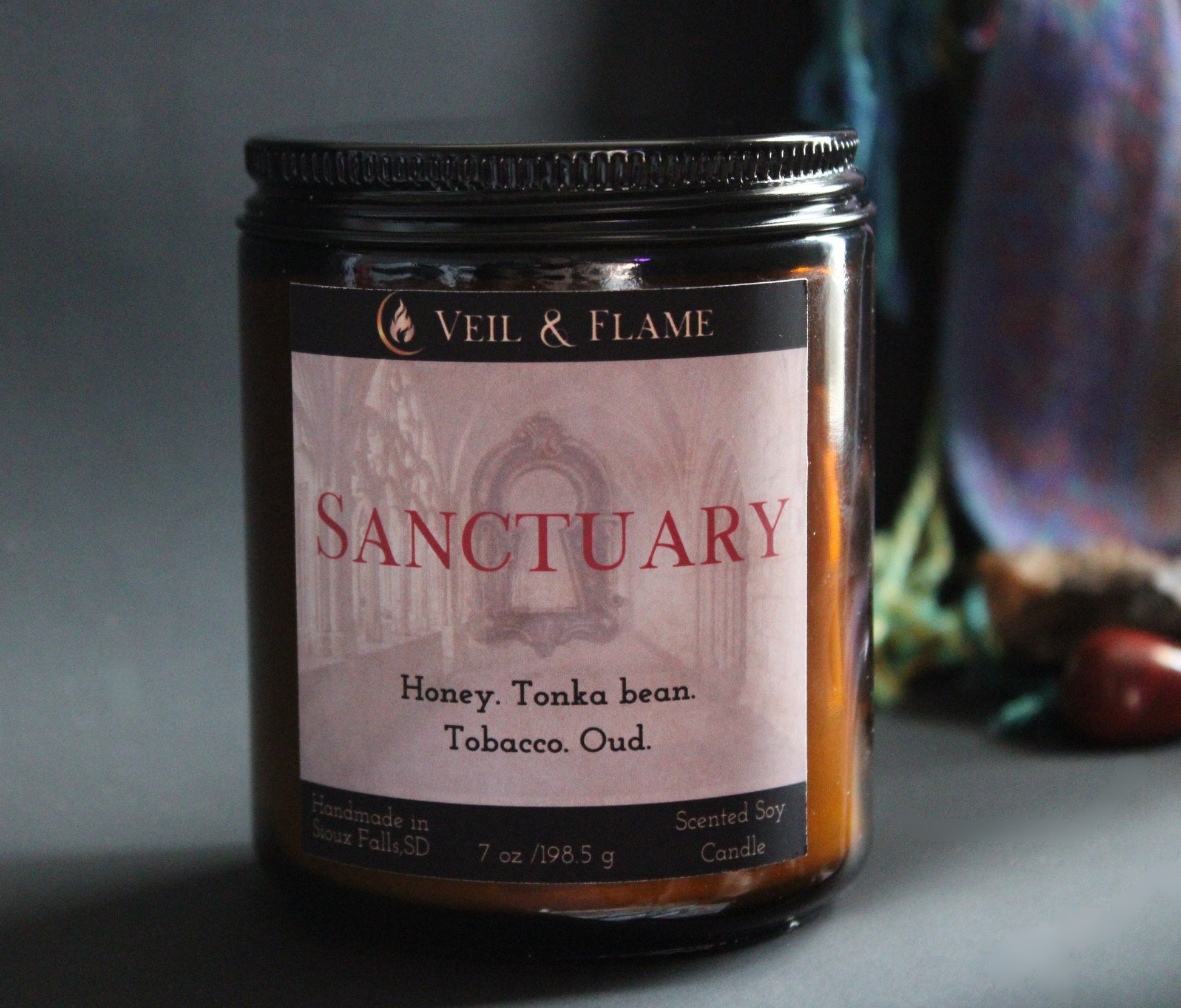 Candle jar labeled 'Sanctuary' by Veil & Flame with a dark background