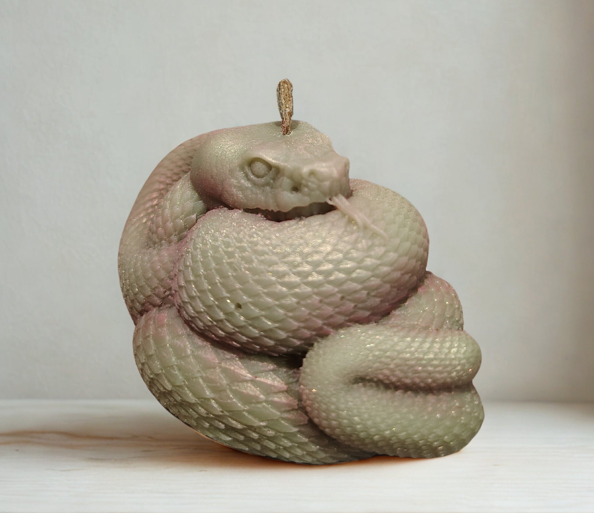 Sculpture of a coiled snake on a plain background