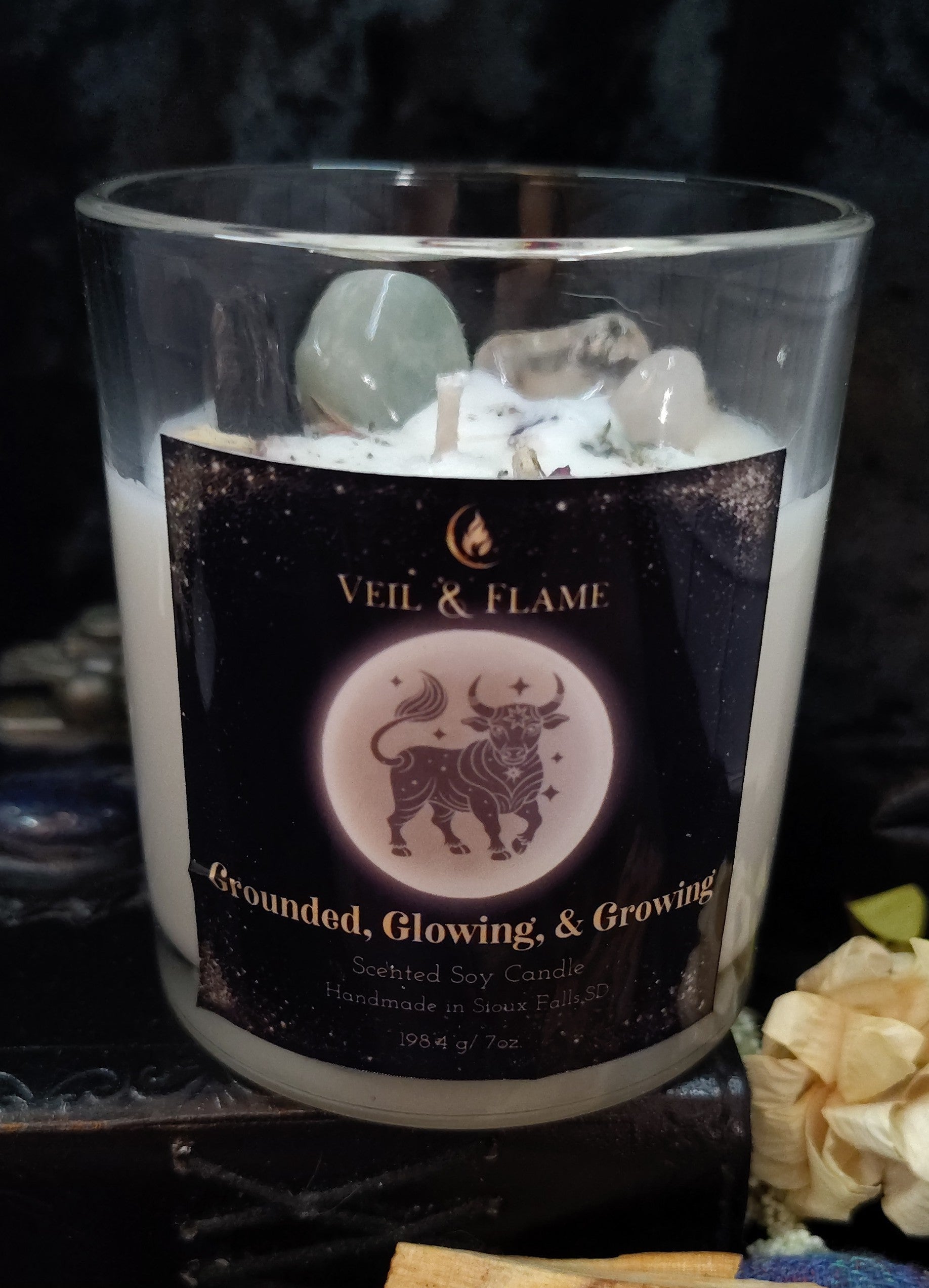 Candle with 'Veil & Flame' label and decorative elements on a dark background